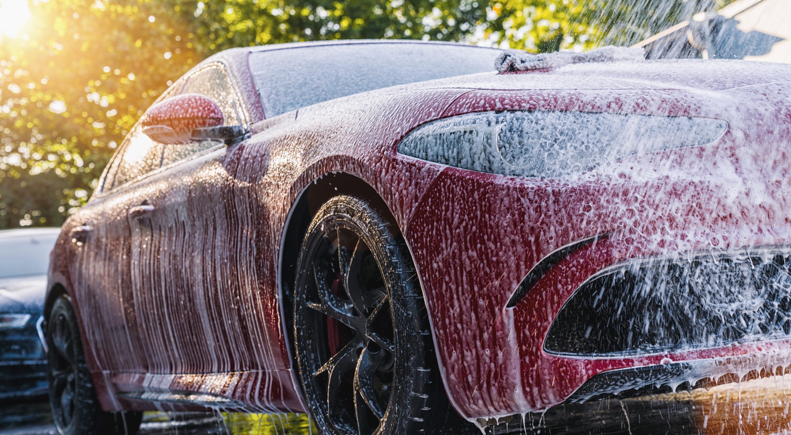 Spraying foam to a red car with high pressure foam gun car wash