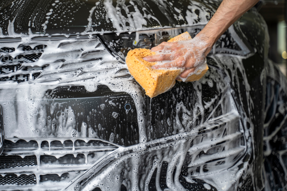 A,Man,Washes,A,Car,With,A,Sponge,In,Foam